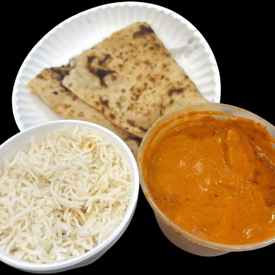 Indian meal with naan bread, white rice, and orange curry in takeout containers.