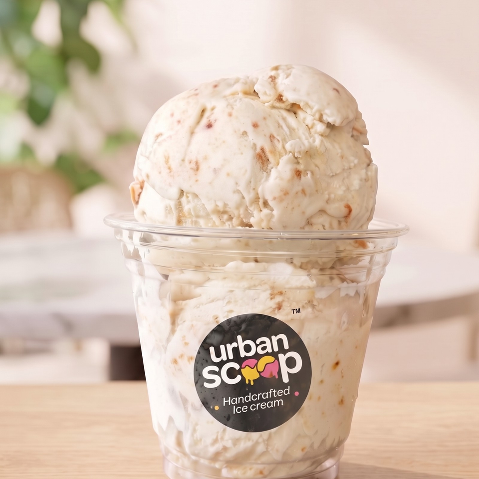 Scoops of handcrafted ice cream in a clear Urban Scoop cup on a wooden table.
